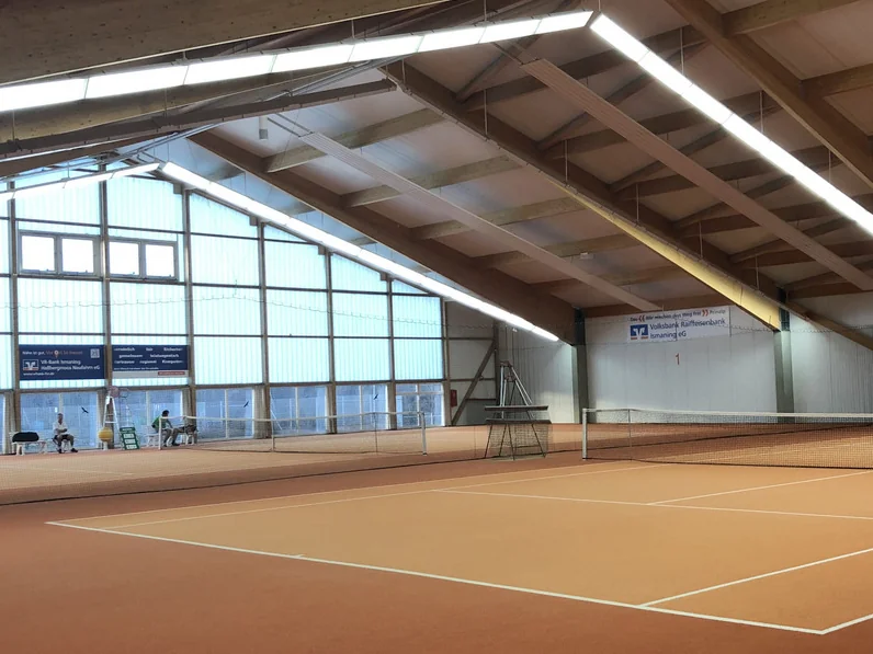 Innenansicht der TCI-Halle mit zwei Sandplätzen, Holzdach-Konstruktion und Glasfront im Hintergrund