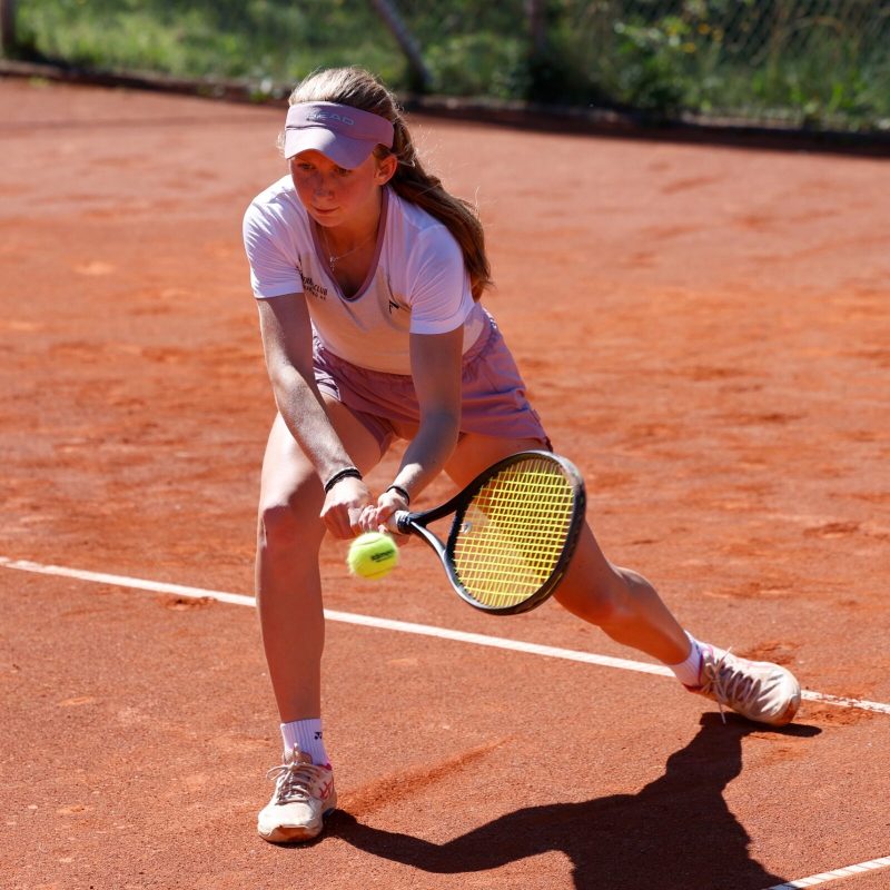 Spielerin streckt sich an der Grundlinie nach einem tiefen Ball